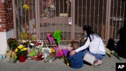 A woman comforts her son while visiting a makeshift memorial outside Star Dance Studio in Monterey Park, California, Jan. 23, 2023. 
