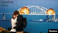 Пара на фоні зображення збудованого Росією Кримського мосту у вогні, Київ, Україна, 8 жовтня 2022 року. Фото: REUTERS/Vladyslav Musiienko/File Photo