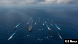 FILE - The aircraft carrier USS Ronald Reagan and the Japanese helicopter destroyer JS Hyuga sail in formation with 16 other ships from the US and Japan in the Philippine Sea, Nov. 8, 2018.