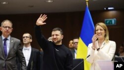 Presiden Ukraina Volodymyr Zelenskyy (tengah), melambaikan tangannya saat Presiden Parlemen Eropa Roberta Metsola (kanan), bertepuk tangan di tengah berlangsungnya KTT Uni Eropa di Parlemen Eropa di Brussel, Belgia, Kamis, 9 Februari 2023. (Foto /Olivier Matthys)