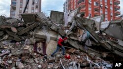 A man walks among rubble as he searches for people in a destroyed building in Adana, Turkey, Feb. 6, 2023. 