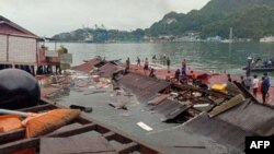 Orang-orang berdiri di atap toko yang runtuh di pelabuhan setelah gempa berkekuatan 5,1 di Jayapura, Papua pada 9 Februari 2023. (Foto: AFP)