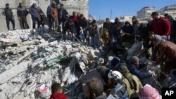 Tim penyelamat dan warga mencari korban gempa di antara puing-puing bangunan yang hancur di kota Harem dekat perbatasan Turki, provinsi Idlib, Suriah (foto: dok). 