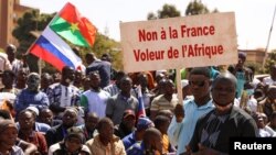A protester holds a sign that reads, 'No to France the thief of Africa' as people gather to show their support to Burkina Faso's new military leader Ibrahim Traore, in Ouagadougou, Burkina Faso, Jan. 20, 2023. 