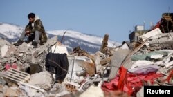 A man sits amid rubble in the aftermath of a deadly earthquake in Kahramanmaras, Turkey February 11, 2023.