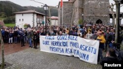 FILE - People stand behind a banner reading "Freedom for our neighbor Pablo Gonzalez. Press Freedom," during a demonstration, after Gonzalez was detained by Polish authorities on espionage charges, in Nabarniz, Spain, March 6, 2022.