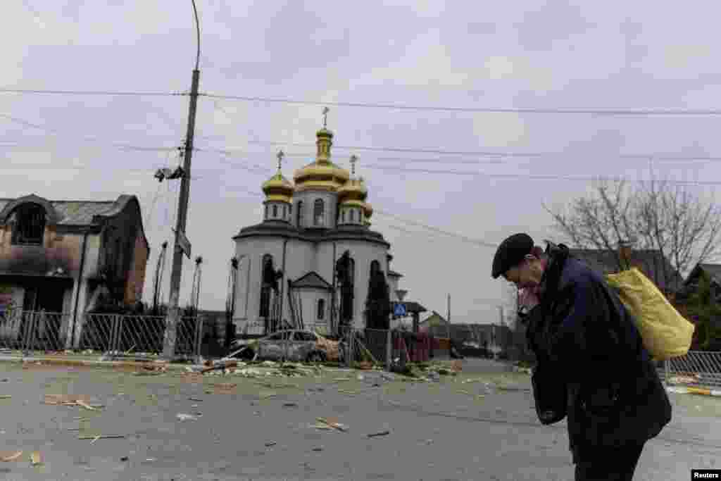 A man takes a pause as he evacuates from the town, on the only escape route used by locals after days of heavy shelling, while Russian troops advance towards the capital, in Irpin, near Kyiv, Ukraine, March 7, 2022.