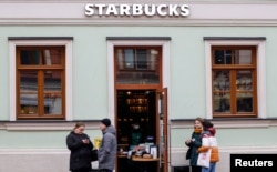 FILE - People wait for their orders outside a Starbucks coffee shop in Moscow, Russia, Oct. 29, 2021.