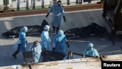 Workers in protective suits move a body to a refrigerated container outside a funeral home, as mortuaries run out of space amid the coronavirus disease (COVID-19) pandemic, in Hong Kong, March 10, 2022. 
