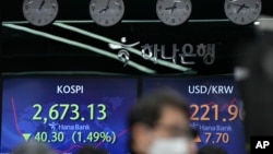 A currency trader watches computer monitors near the screens showing the Korea Composite Stock Price Index (KOSPI), left, and the foreign exchange rate between U.S. dollar and South Korean won at a foreign exchange dealing room in Seoul, South Korea, Monday, March 7, 2022. The price of oil jumped more than $10 a barrel and shares were sharply lower Monday as the conflict in Ukraine deepened amid mounting calls for harsher sanctions against Russia. (AP Photo/Lee Jin-man)