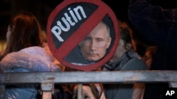 Seorang gadis memegang plakat yang menggambarkan Presiden Rusia Vladimir Putin saat memprotes invasi Rusia ke Ukraina di Tel Aviv, Israel, 5 Maret 2022. (Foto: AP)
