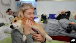 Olga Okhrimenko, who fled the Russian invasion from Kharkiv on March 1, holds her dog Knolly as they sit inside a ballroom converted into a makeshift refugee shelter, in Suceava, Romania, March 4, 2022.