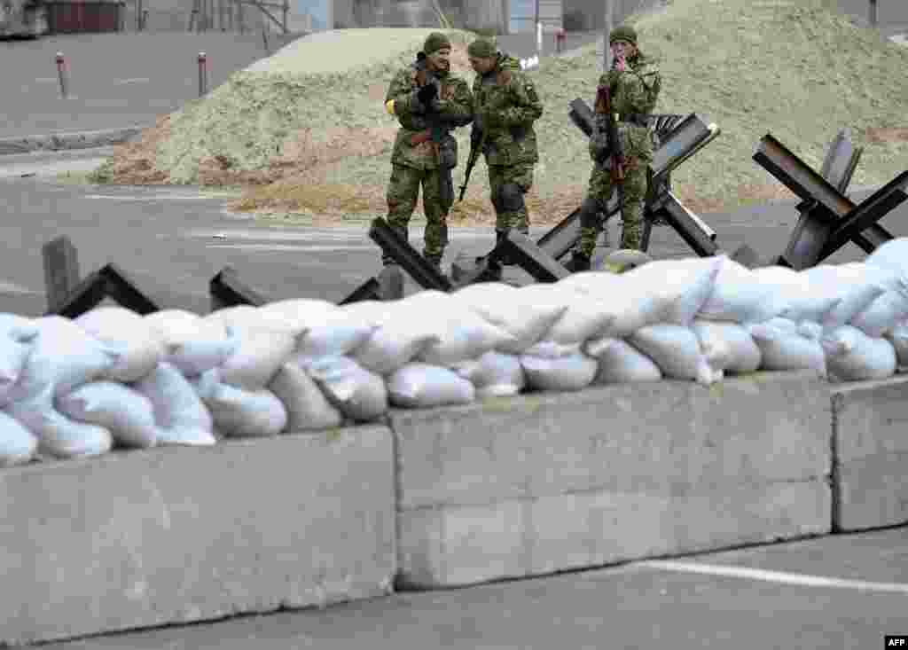 Members of the Ukrainian Territorial Defense Forces, the military reserve of the Ukrainian Armed Forces, stand guard next to anti-tank structures blocking the streets of the center of Kyiv, March 6, 2022.