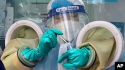 FILE - A worker handles a coronavirus test sample at a private testing site in Beijing, Wednesday, Jan. 26, 2022.
