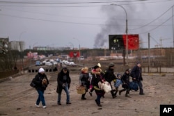 A Ukrainian police officer helps people as artillery echoes nearby while fleeing Irpin in the outskirts of Kyiv, Ukraine, March 7, 2022.
