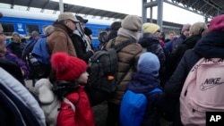 Parents accompany children and teenagers as they board a train after leaving Kyiv's Central Children's Hospital, following its evacuation, in Kyiv, Ukraine, Monday, March 7, 2022.