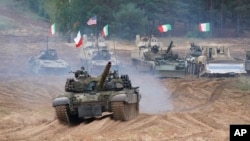 FILE - Military vehicles and tanks of Poland, Italy, and the United States move during NATO military exercises at a training ground in Kadaga, Latvia, Sept. 13, 2021.