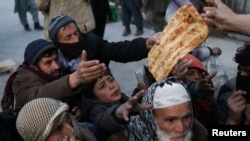 FILE - People reach out to receive bread, in Kabul, Afghanistan, Jan. 31, 2022. 