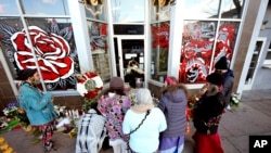 FILE - Mourners gather outside a tattoo parlor, one of the scenes of a shooting spree by Lyndon McCleod, in Denver on on Dec. 28, 2021. 