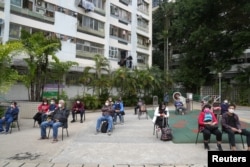 People wearing face masks wait for their swab samples to be collected at a makeshift testing site for COVID-19, in Hong Kong, China, Feb. 15, 2022.