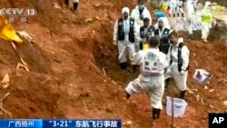 In this image from video run by China's CCTV, search-and-rescue workers stand where they recovered the flight data recorder at the China Eastern flight crash site in Tengxian County, March 27, 2022, in southern China's Guangxi Zhuang Autonomous Region.