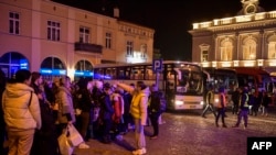 People wait to board buses taking them to Warsaw outside the train station in Przemysl, which became a main transfer hub for refugees fleeing Russia's invasion of Ukraine, March 12, 2022.