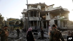 FILE- Afghan security personnel inspect a damaged building in the aftermath of an attack in Kabul, Afghanistan, Aug. 4, 2021.
