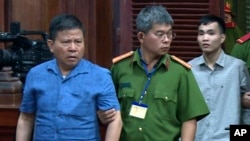 Công dân Úc Châu Văn Khảm (trái) bị giải tới tòa xử án ở TPHCM hôm 11/11/2019. Úc đang thúc giục Việt Nam thả tự do cho người đàn ông 72 tuổi đang thụ án 12 năm tù tại đây vì lý do sức khỏe. (Nguyen Thanh Chung/VNA via AP)