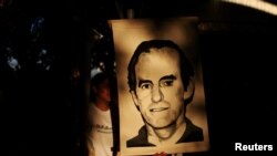Un joven sostiene un retrato del jesuita Ignacio Ellacuria antes de una procesión que conmemora el 28º aniversario del asesinato de seis sacerdotes jesuitas y dos empleados, que fueron ejecutados por las fuerzas militares durante la guerra civil en El Salvador. [Foto de archivo]