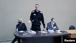 FILE - Alexei Navalny, lawyers Olga Mikhailova and Vadim Kobzev are seen on a screen via a video link during a court hearing at the IK-2 male correctional facility, in the town of Pokrov in Vladimir Region, Russia, Feb. 15, 2022.