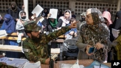 A Taliban fighter talks with a woman at the government passport office in Kabul, Oct. 17, 2021.