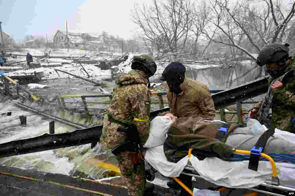Ukrainian soldiers carry a wounded woman during the evacuation by civilians of the city of Irpin, northwest of Kyiv, March 8, 2022.