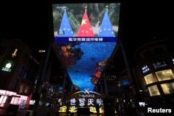 A giant screen shows news footage of Chinese national flags and European Union flags during an EU-China virtual summit, in Beijing, China, April 1, 2022.