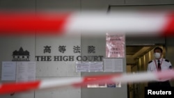 FILE - A guard stands behind cordons before a hearing at the High Court in Hong Kong, March 11, 2021.