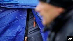FILE - A refugee that fled the conflict from neighboring Ukraine sticks out her hand from a waiting area tent at the Romanian-Ukrainian border, in Siret, Romania, March 3, 2022. 