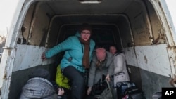 Pengungsi dari Mariupol turun dari mobil van yang mereka gunakan sebagai transportasi setibanya di sebuah pusat pengungsi di Zaporizhia, Ukraina, Jumat, 25 Maret 2022. (AP Photo/Evgeniy Maloletka)