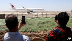 FILE - Residents watch as a China Eastern passenger jet prepares to take off on a test flight from the new Beijing Daxing International Airport on Monday, May 13, 2019. 
