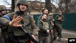 Ukrainian President Volodymyr Zelenskyy (center) walks in the town of Bucha, just northwest of Ukraine's capital, Kyiv, on April 4, 2022.