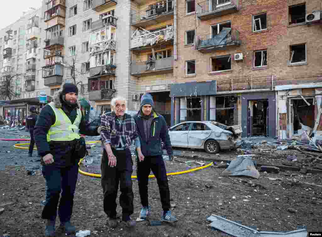 People help a wounded resident of a house destroyed by shelling in Kyiv, March 14, 2022