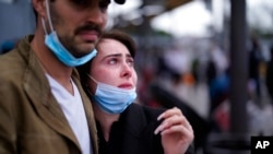 A woman from Ukraine stands at the border with her fiance from the United States as she waits to ask for asylum, March 10, 2022, in Tijuana, Mexico.