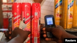 FILE - A customer holds his mobile phone as he prepares to pay for mosquito sprays at Makola market, one of the country's largest trading centers in Accra, Ghana, March 26, 2022.