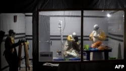 FILE - Health workers treat an unconfirmed Ebola patient, inside a MSF (Doctors Without Borders) supported Ebola Treatment Center (ETC) in Butembo, Democratic Republic of the Congo, Nov. 3, 2018. Attackers set fire to an Ebola treatment center in Katwa late Sunday.