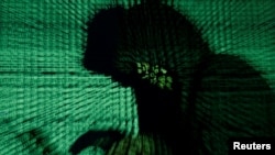 FILE - A man holds a laptop computer as cyber code is projected on him in this illustration picture taken May 13, 2017.