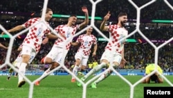 Croatia players celebrate as Brazil's Marquinhos, right, missed a penalty kick to secure the World Cup victory for Croatia on Dec. 9, 2022. 