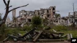 Ammunition boxes lie outside a destroyed school on the outskirts of a recently liberated village outskirts of Kherson, in southern Ukraine, Nov. 16, 2022. 