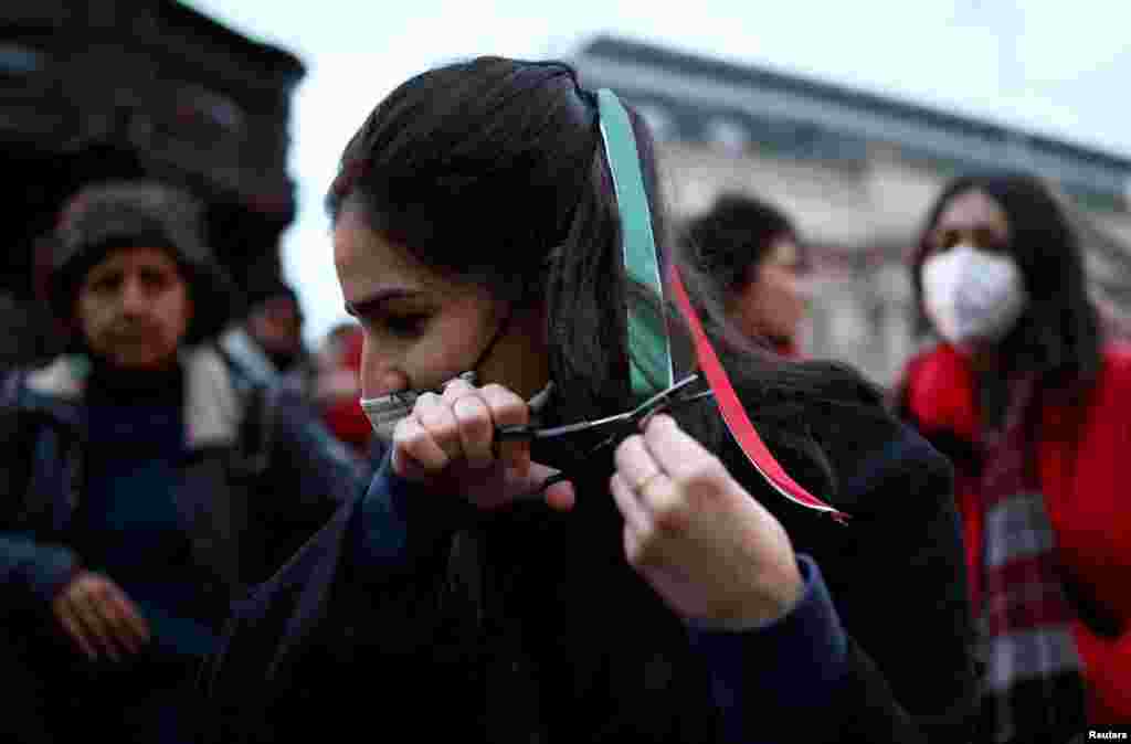 زن جوان معترضی در تظاهرات همبستگی در لندن گیسوان خود را می&zwnj;برد، شنبه ۵ آذر&nbsp;