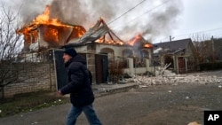 A local resident runs past a burning house hit by the Russian shelling in Kherson, Ukraine, Jan. 6, 2023.