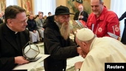 Paus Fransiskus mencium tangan seorang pria saat bertemu delegasi Penghargaan Bunda Teresa sekaligus perayaan ulang tahunnya yang ke-86 di Vatikan, Sabtu, 17 Desember 2022. (Foto: Vatican Media via Reuters)