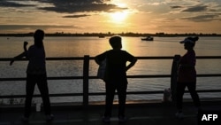 FILE - Cambodian women exercise by the Mekong River at sunrise in Phnom Penh on Aug. 3, 2022.