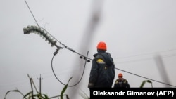 Para pekerja memperbaiki kabel jaringan listrik tegangan tinggi yang terputus akibat serangan misil dekat Odessa di Ukraina di tengah invasi Rusia ke Ukraina pada 7 Desember 2022. (Foto: Oleksandr Gimanov/AFP)UKRAINE-RUSSIA-CONFLICT-WAR-ENERGY